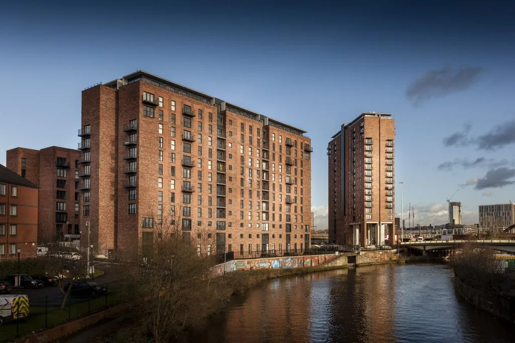 Completed Wilburn Basin apartment buildings and glazing beside the River Irwell
