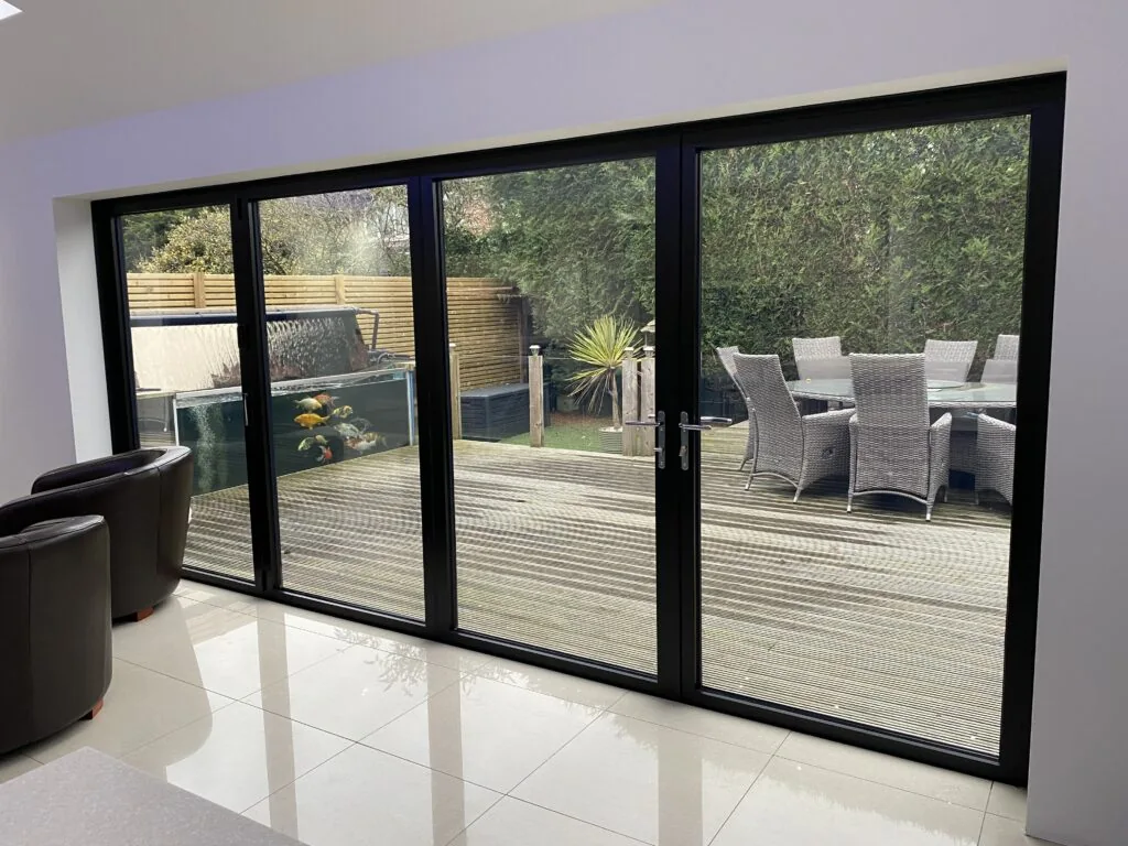 Black-framed bifold doors opening onto a garden terrace